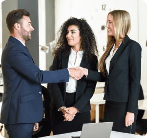 Three business people shaking hands in an office, symbolizing a successful and professional agreement.